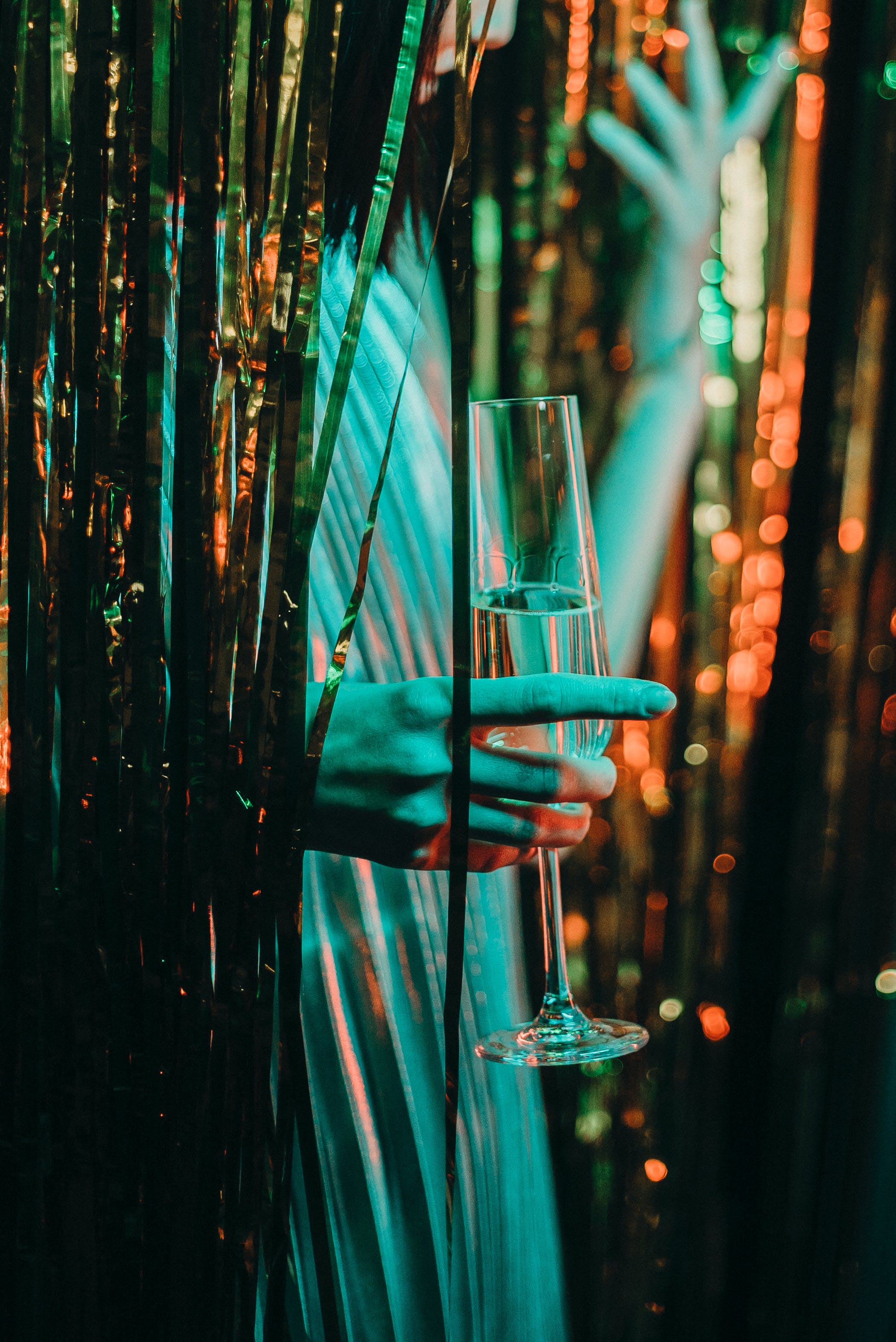 Eine Dame, die ein Sektglas hält, während sie durch einen Lametta Vorhang geht